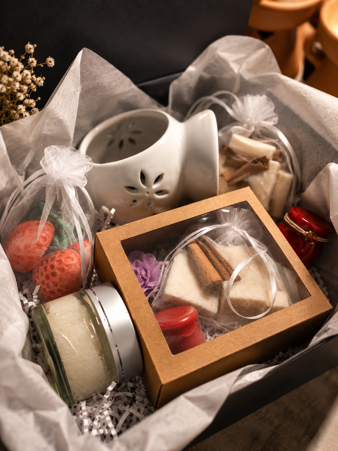 A curated Cozy Box with wax burner, soaps, wax melts and bath scrub on tissue paper